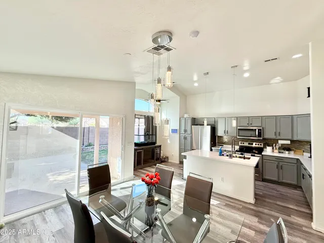 a kitchen with stainless steel appliances kitchen island granite countertop a table and chairs