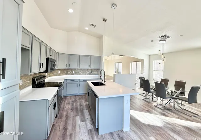 a large kitchen with lots of counter top space a sink appliances and cabinets