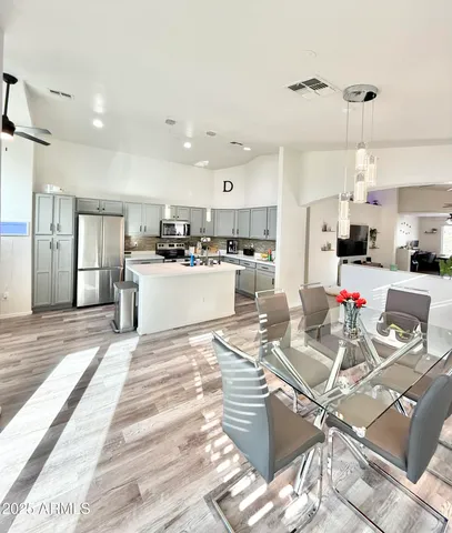 a room with lots of white furniture and kitchen view