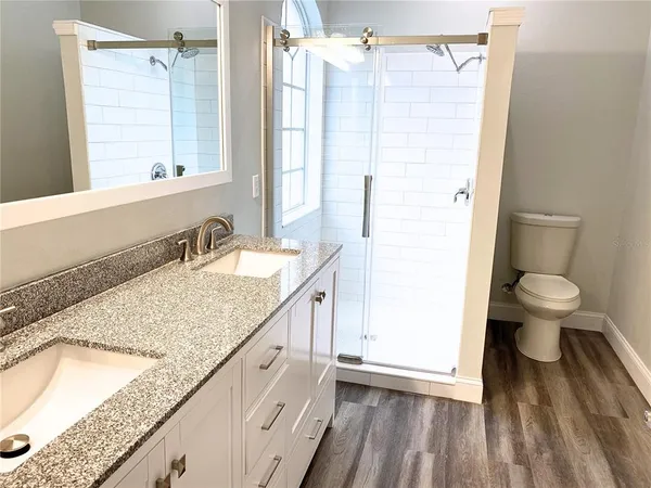 a bathroom with a granite countertop sink a toilet and shower