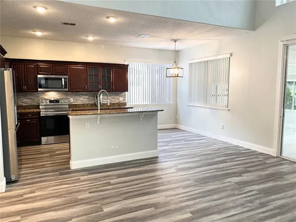 a kitchen with stainless steel appliances granite countertop a sink a stove top oven and cabinetry