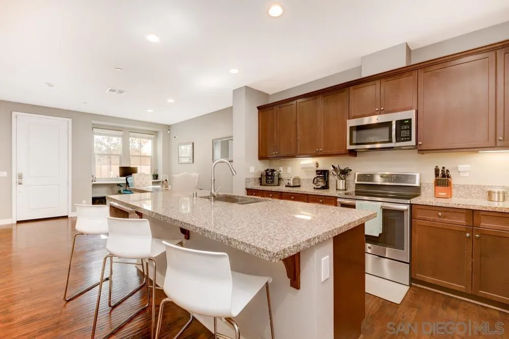 7508 Eagle Drive Santee, CA 92071 - Photo 11 of 25 a kitchen with stainless steel appliances granite countertop a stove top oven a sink a refrigerator white cabinets and chairs with wooden floor