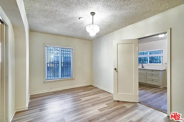 an empty room with wooden floor cabinet and windows