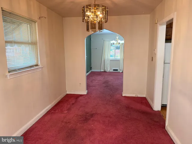 an empty room with chandelier fan and windows