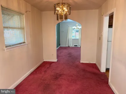 an empty room with chandelier fan and windows