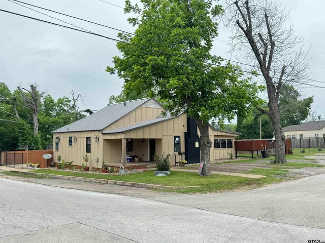 a front view of a house with a garden and trees