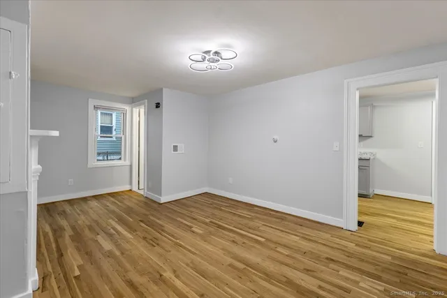 a view of an empty room with wooden floor and a window