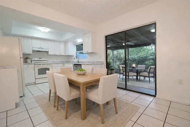 a kitchen with stainless steel appliances granite countertop a stove a refrigerator a dining table and chairs next to a window