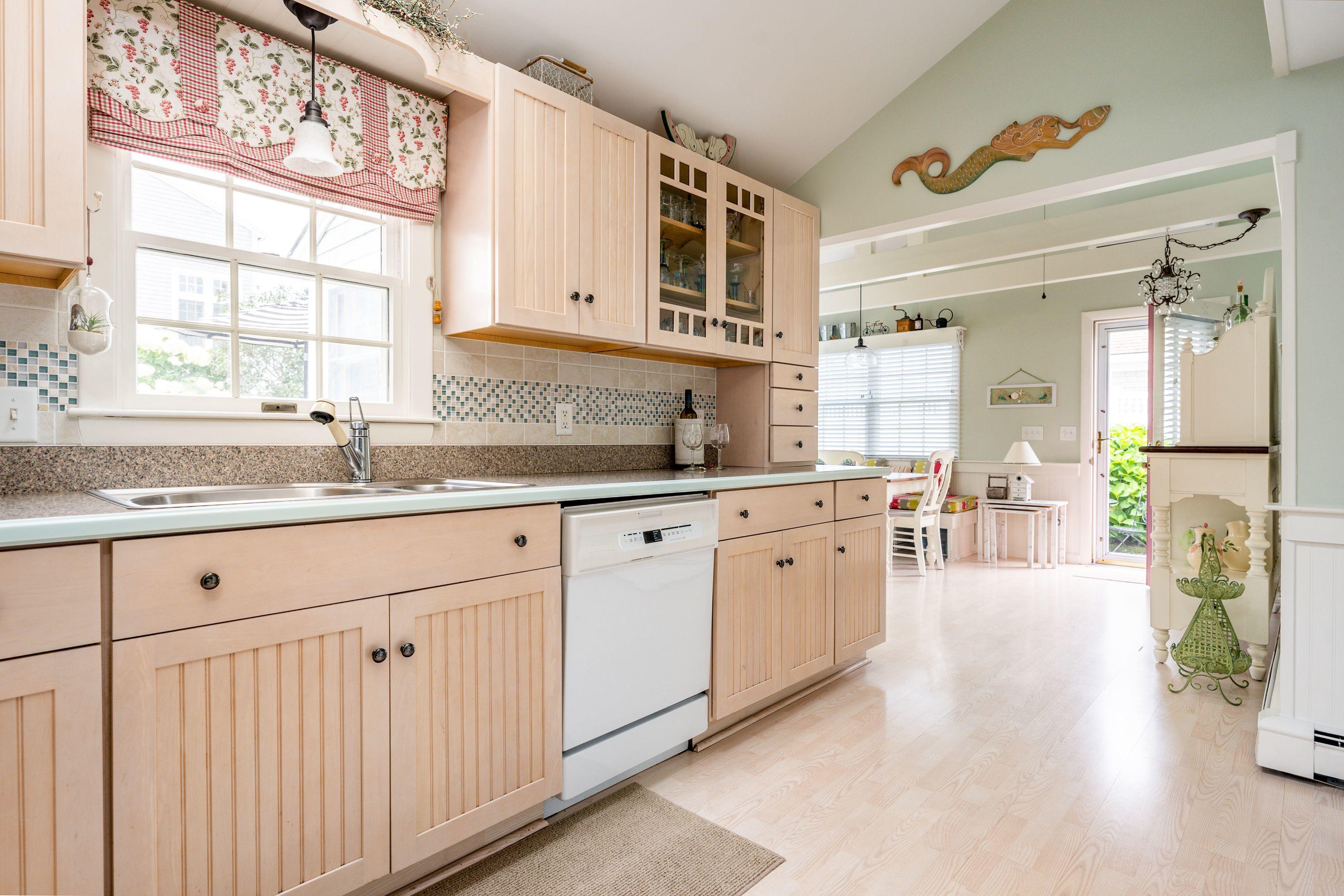 85 Surfside Road West Dennis, MA 02670 - Photo 8 of 34 a large white kitchen with granite countertop a sink white cabinets and a window