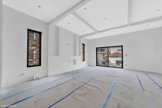 a view of an empty room with window and dresser