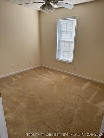 an empty room with a chandelier fan and windows