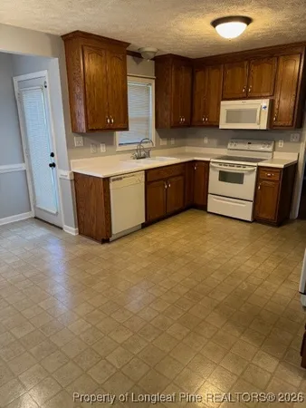 a kitchen with stainless steel appliances a sink a stove a refrigerator cabinets and a window