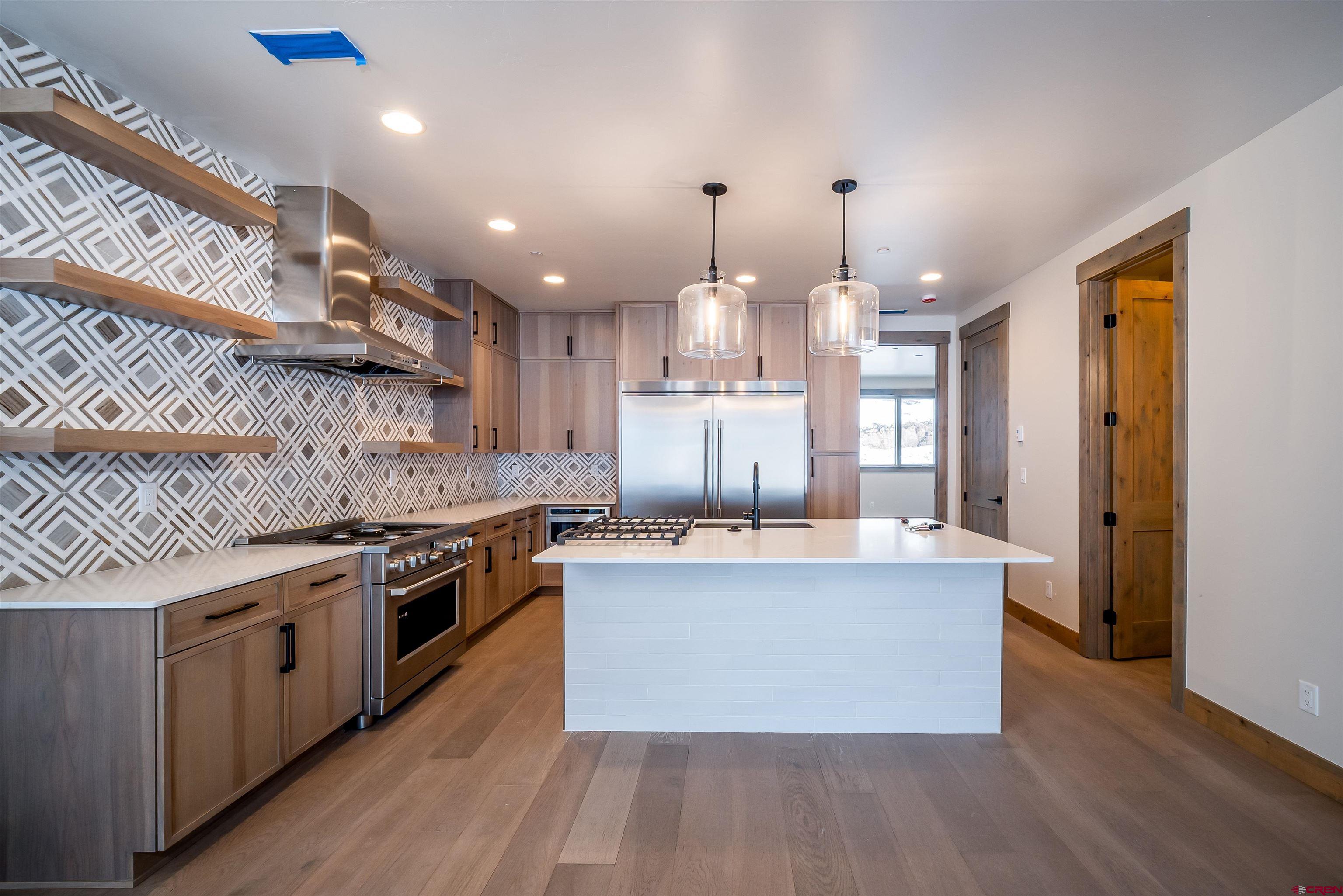 93 Travertine Trail Durango, CO 81301 - Photo 8 of 44 a large kitchen with kitchen island a stove a sink dishwasher and refrigerator with wooden floor