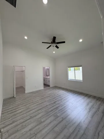 a view of empty room with wooden floor and fan