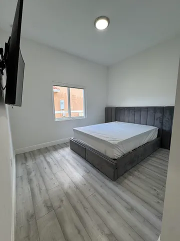 a spacious bedroom with a bed and flat screen tv
