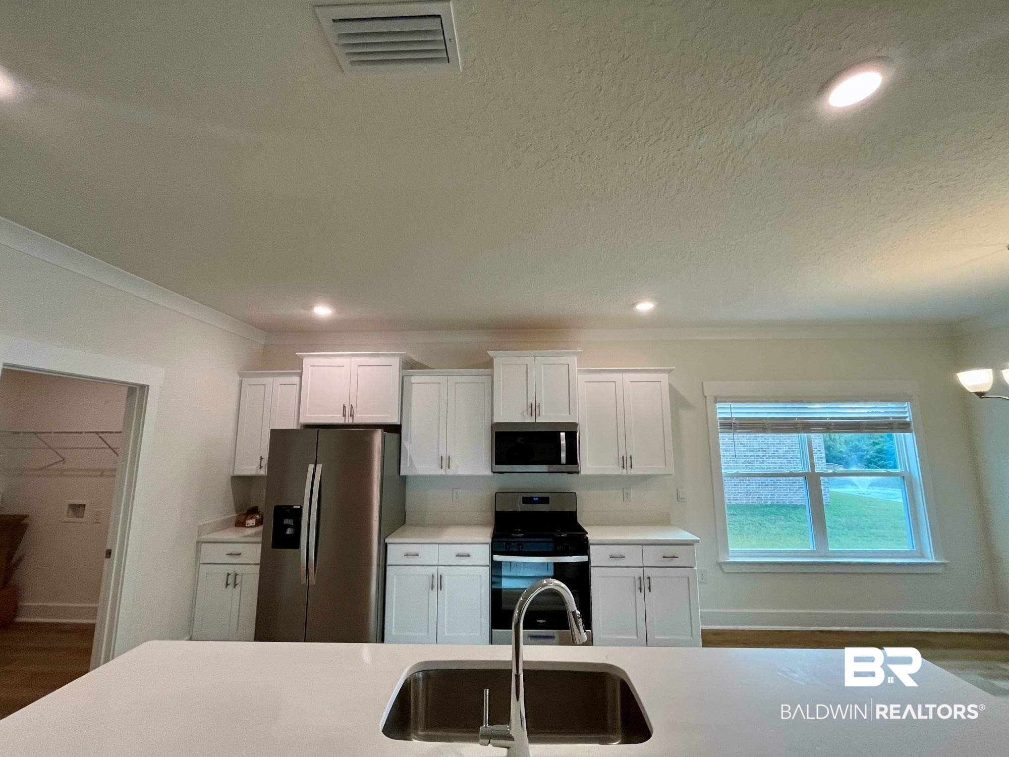 337 Barndling Street Fairhope, AL 36532 - Photo 14 of 34 Kitchen with dark wood-type flooring, white cabinets, sink, crown molding, and appliances with stainless steel finishes