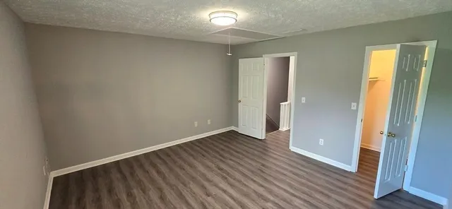 an empty room with wooden floor and a bathroom