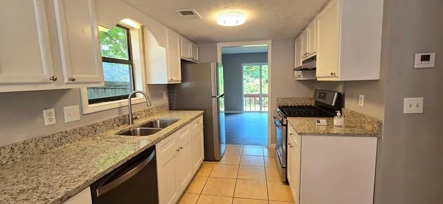 a kitchen with stainless steel appliances granite countertop a sink stove and refrigerator