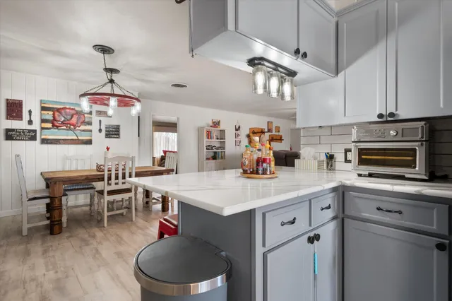 a kitchen with stainless steel appliances granite countertop a sink dishwasher a dining table and chairs with wooden floor