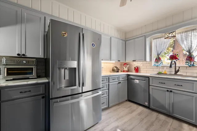 a kitchen with granite countertop stainless steel appliances a sink cabinets and a window