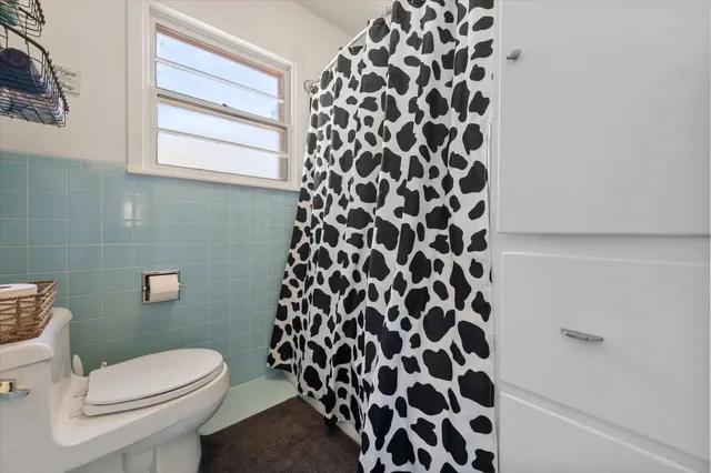 a white toilet sitting next to a shower curtain