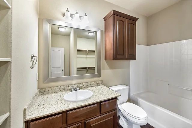 a bathroom with a granite countertop sink toilet and shower
