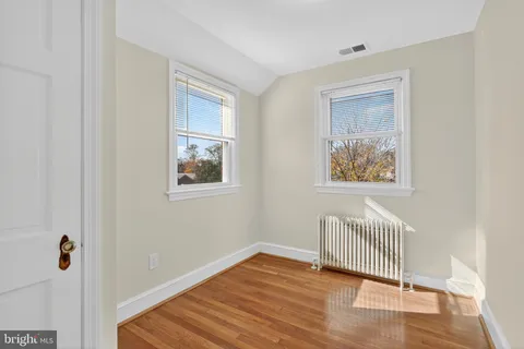 a view of a hallway with wooden floor and a bedroom