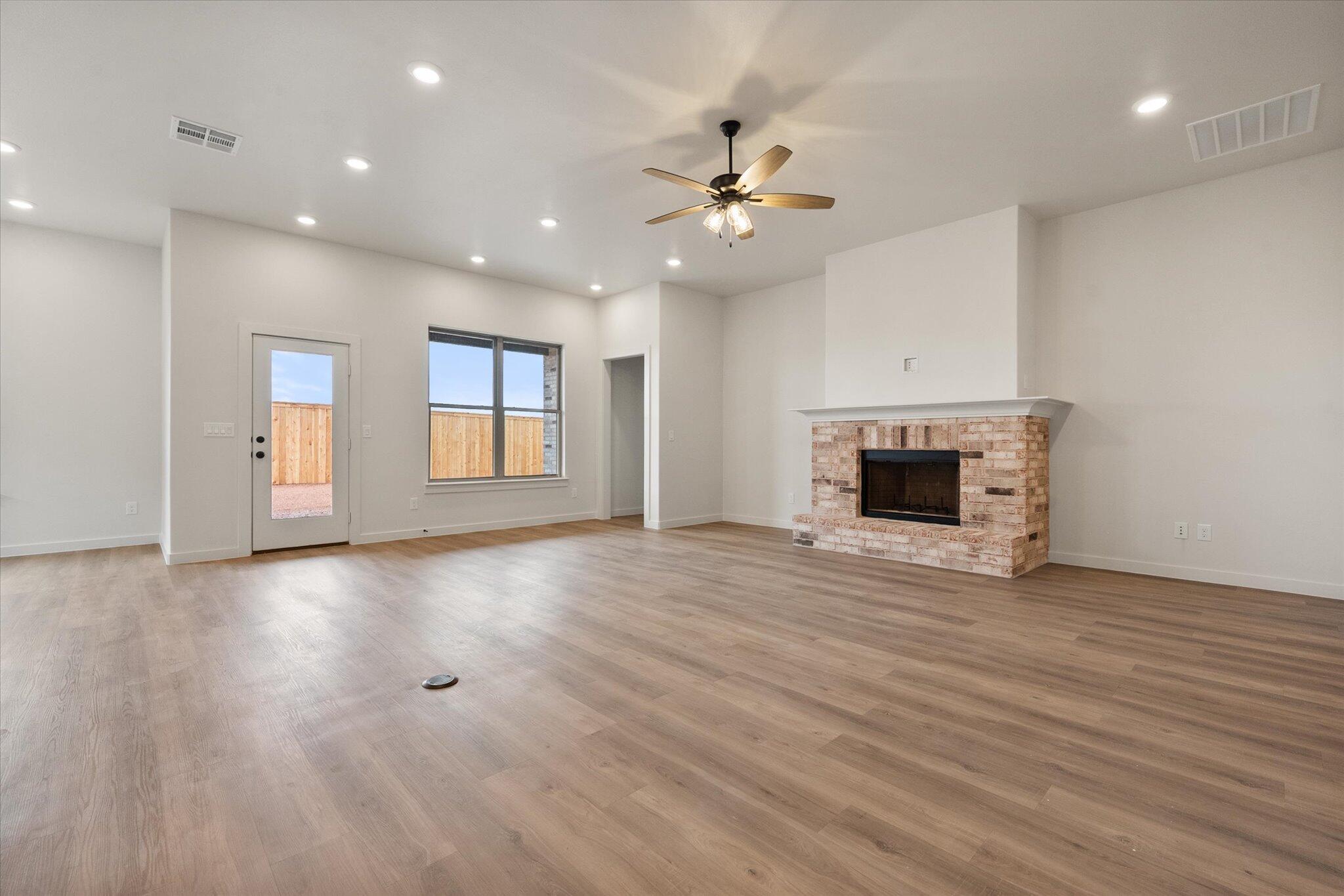 2901 Tractor Avenue Wolfforth, TX 79382 - Photo 4 of 25 an empty room with wooden floor fireplace and windows