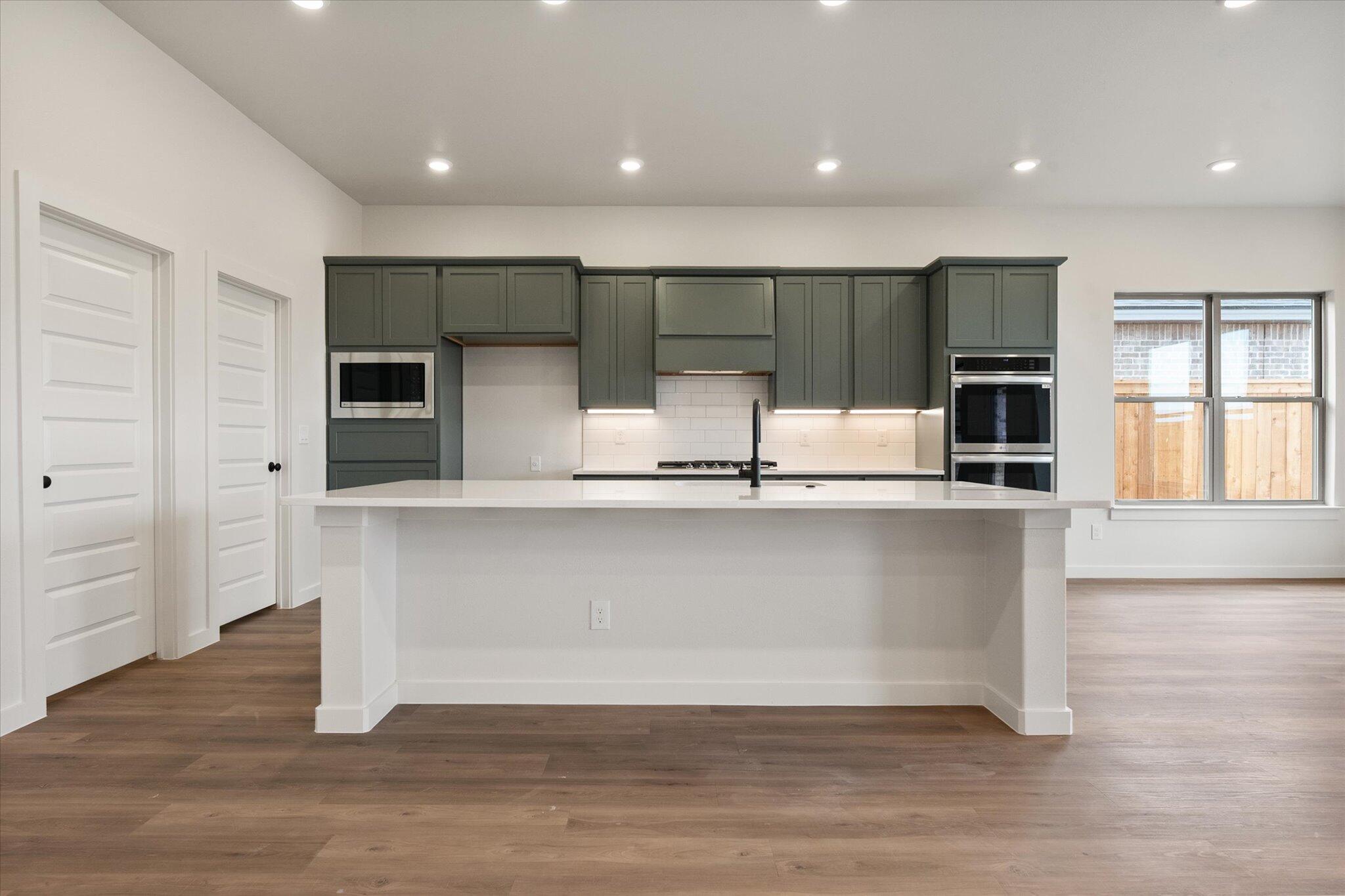 2901 Tractor Avenue Wolfforth, TX 79382 - Photo 8 of 25 an empty room with wooden floor and kitchen view