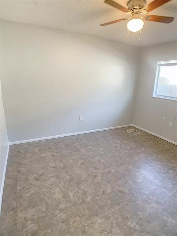 530 5th Avenue West, Unit C Palmetto, FL 34221 - Photo 22 of 27 an empty room with a chandelier fan and windows