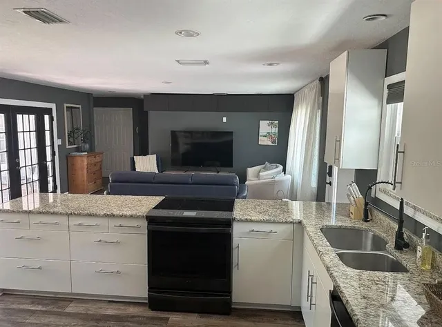 a kitchen with granite countertop a sink stainless steel appliances and cabinets