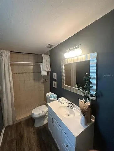 a bathroom with a sink a toilet a mirror and shower