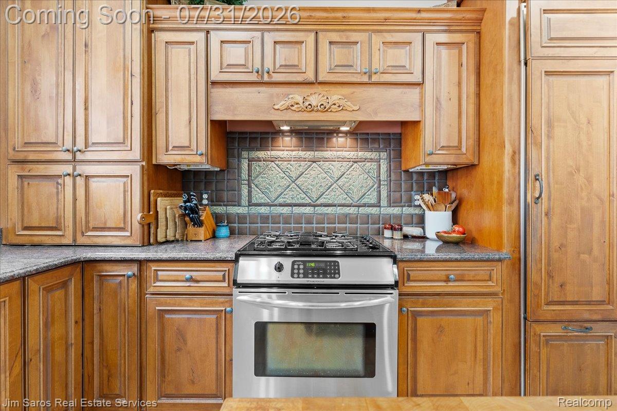 Kitchen featuring extensive wood cabinetry, stainless steel range, and granite-style countertops