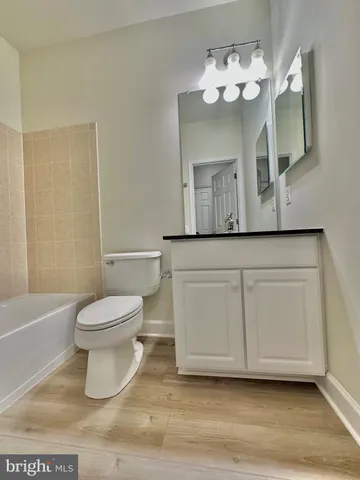 a view of a hallway with wooden floor and a bathroom
