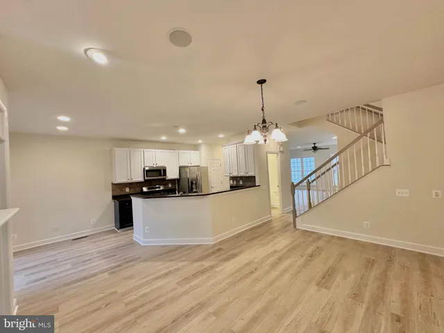 a view of an empty room with wooden floor fireplace and a window