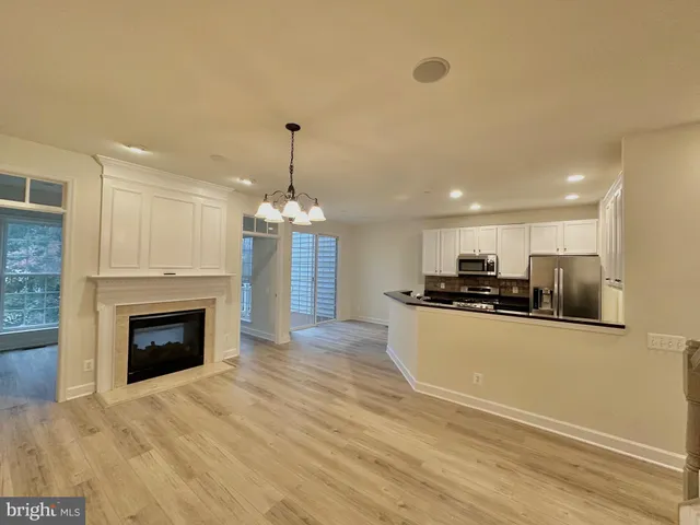 a view of an empty room with wooden floor fireplace and a window