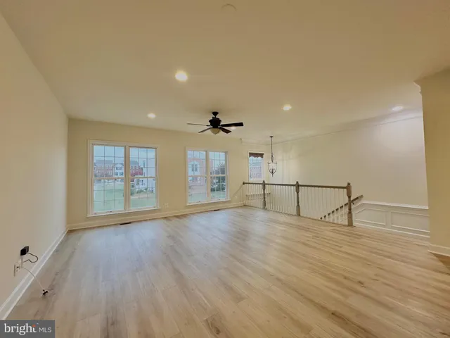 an empty room with wooden floor fan and windows