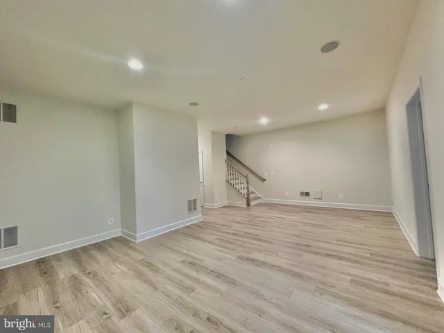 a kitchen with stainless steel appliances granite countertop a sink a stove top oven a refrigerator with white cabinets and wooden floor