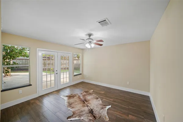 a view of an empty room with wooden floor and a window