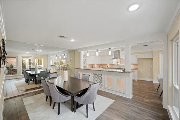 a kitchen with a dining table chairs and wooden floor