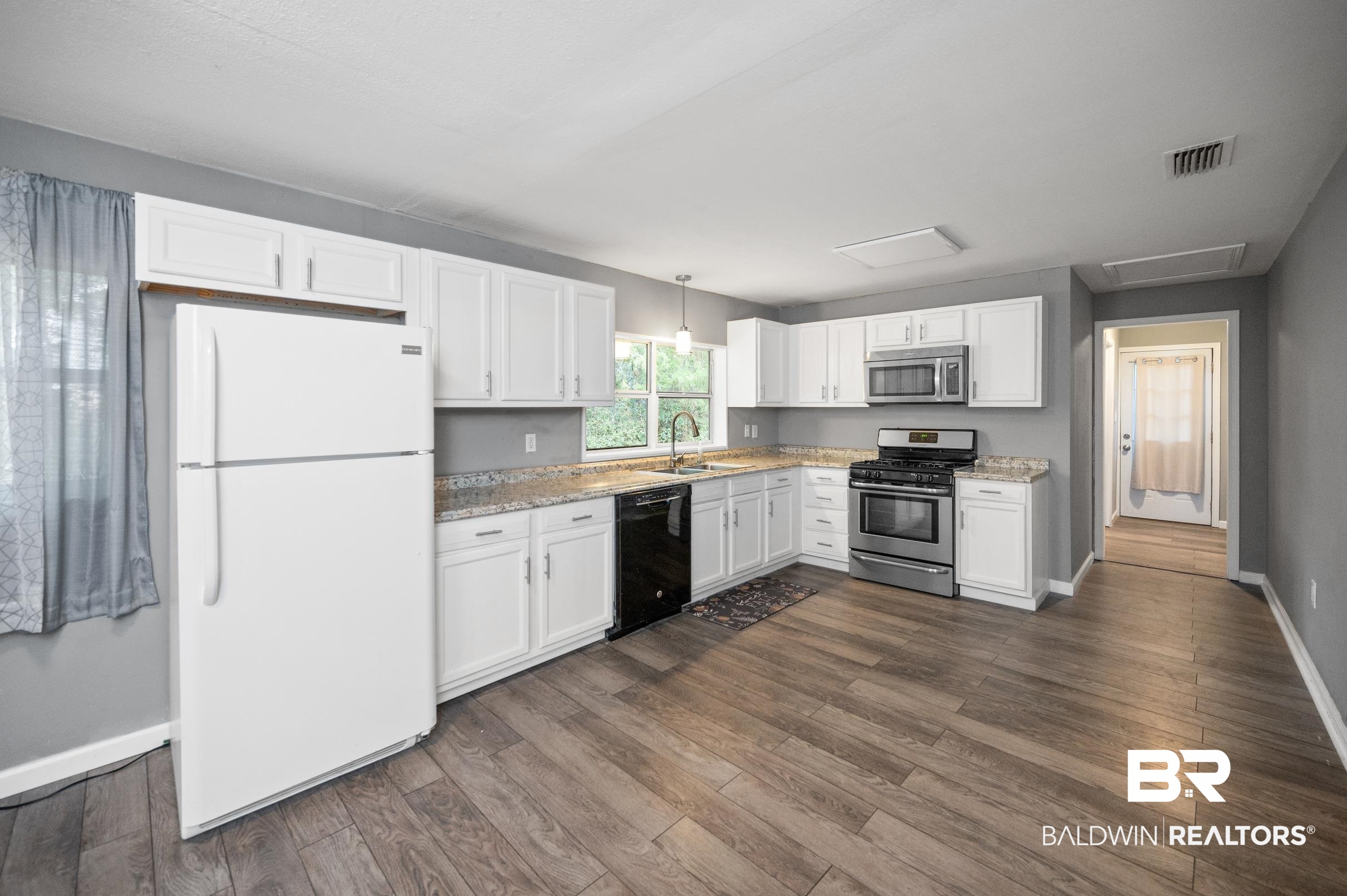 906 North Cedar Street Foley, AL 36535 - Photo 6 of 24 Kitchen featuring appliances with stainless steel finishes, dark hardwood / wood-style flooring, hanging light fixtures, sink, and white cabinets