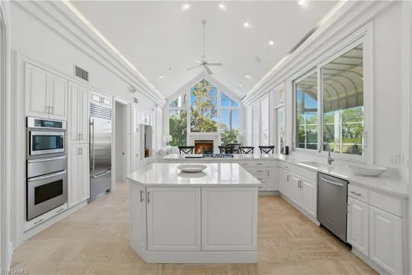 a large white kitchen with a large window and stainless steel appliances