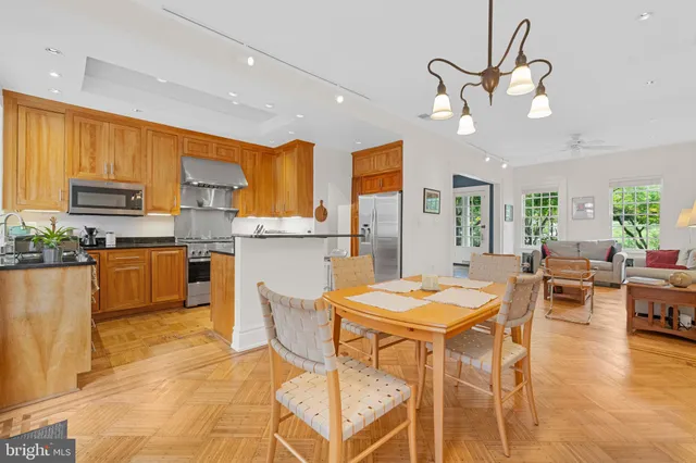 a kitchen with stainless steel appliances kitchen island granite countertop a table chairs and a refrigerator