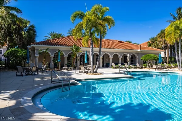 a view of a swimming pool with couches chairs under an umbrella