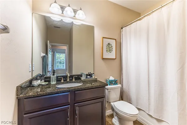 a bathroom with a granite countertop sink a toilet and a mirror