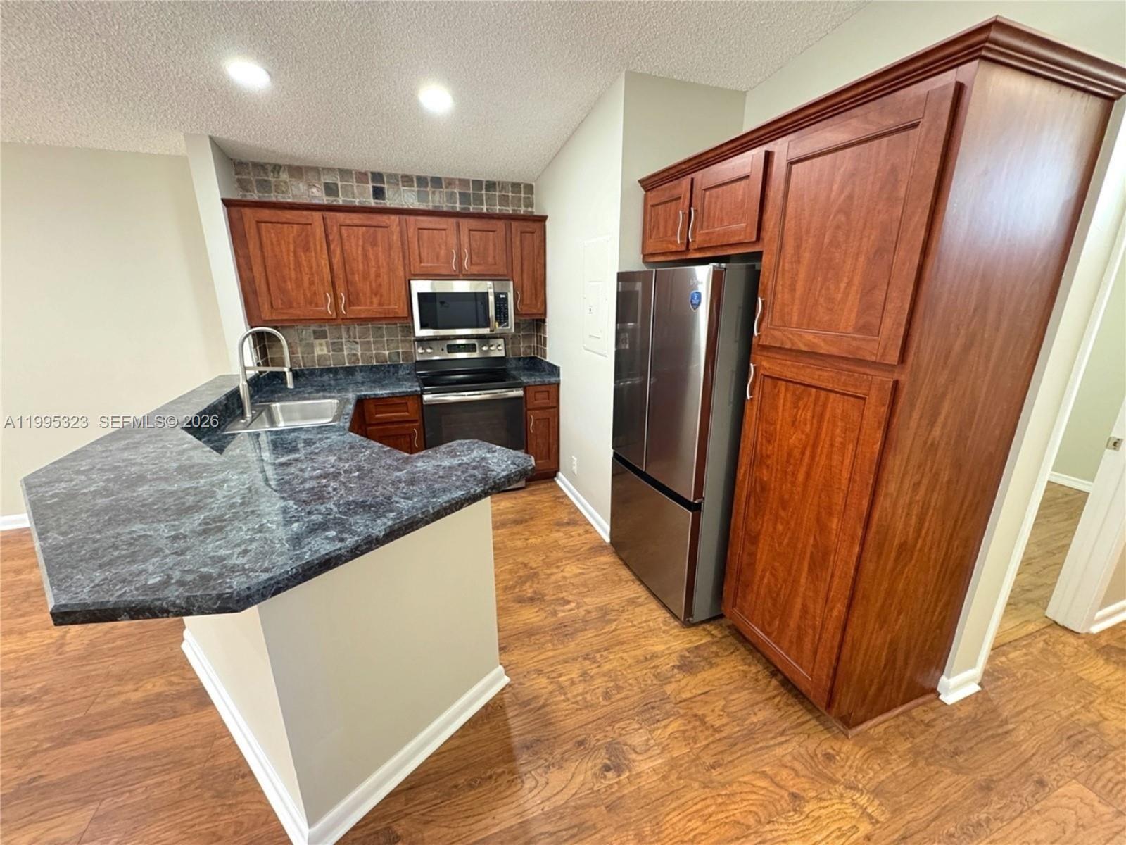 22278 Misty Woods Way, Unit 22278 Boca Raton, FL 33428 - Photo 3 of 20 a kitchen with stainless steel appliances granite countertop a refrigerator and a sink
