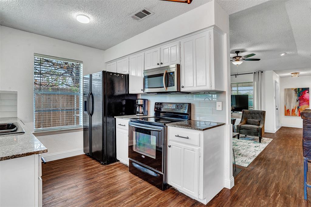 9831 Windy Ridge Road Frisco, TX 75033 - Photo 19 of 31 Kitchen with white cabinetry, stainless steel microwave, black electric range, and wood-finish flooring