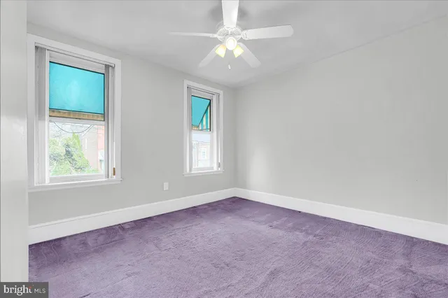 an empty room with windows and fan