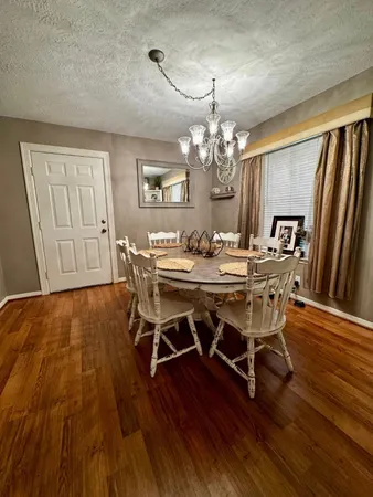 a dining room with wooden floor a chandelier a wooden table and chairs