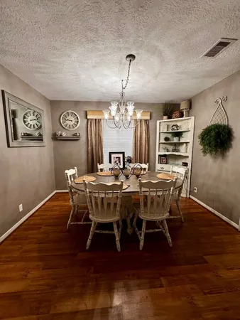 a dining room with wooden floor a chandelier a wooden table and chairs